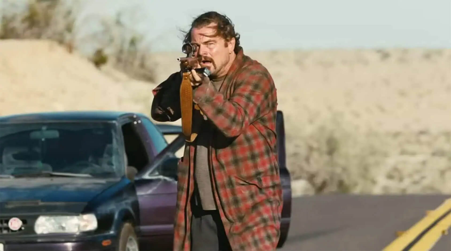 A still from One Battle After Another – Leonardo DiCaprio aiming a rifle